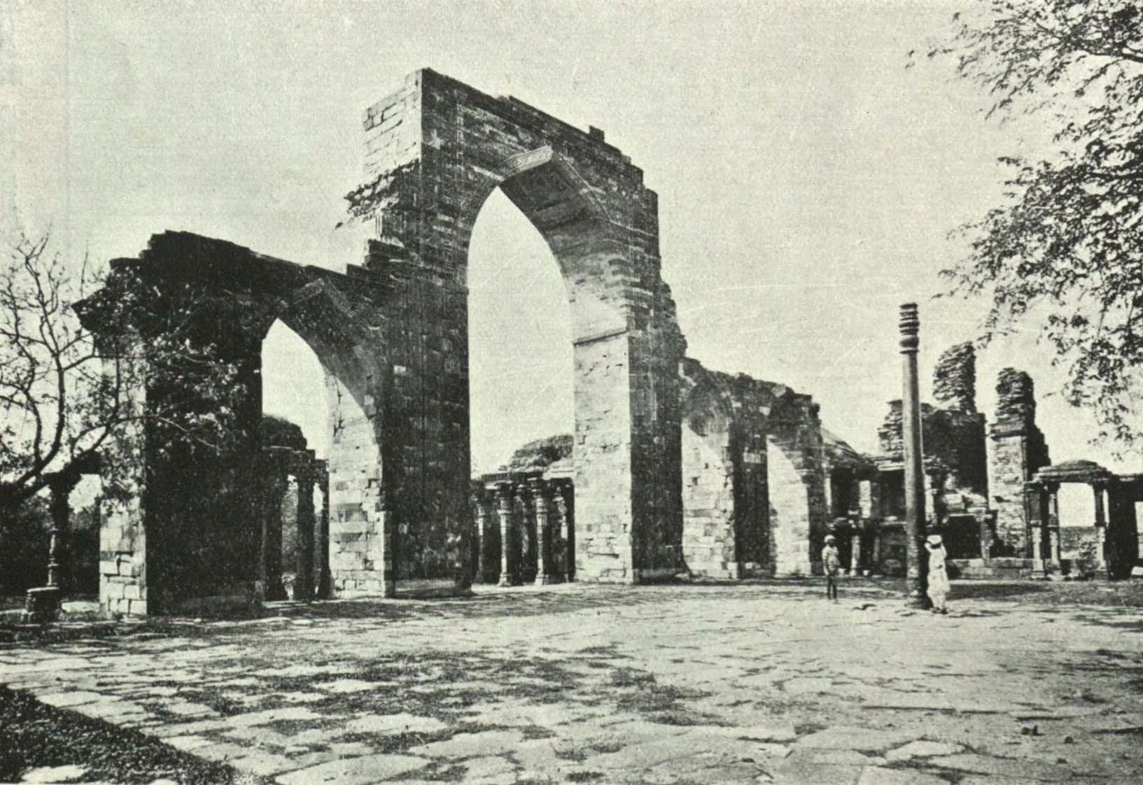Historical photograph of the Iron Pillar with Qutub Minar in background
