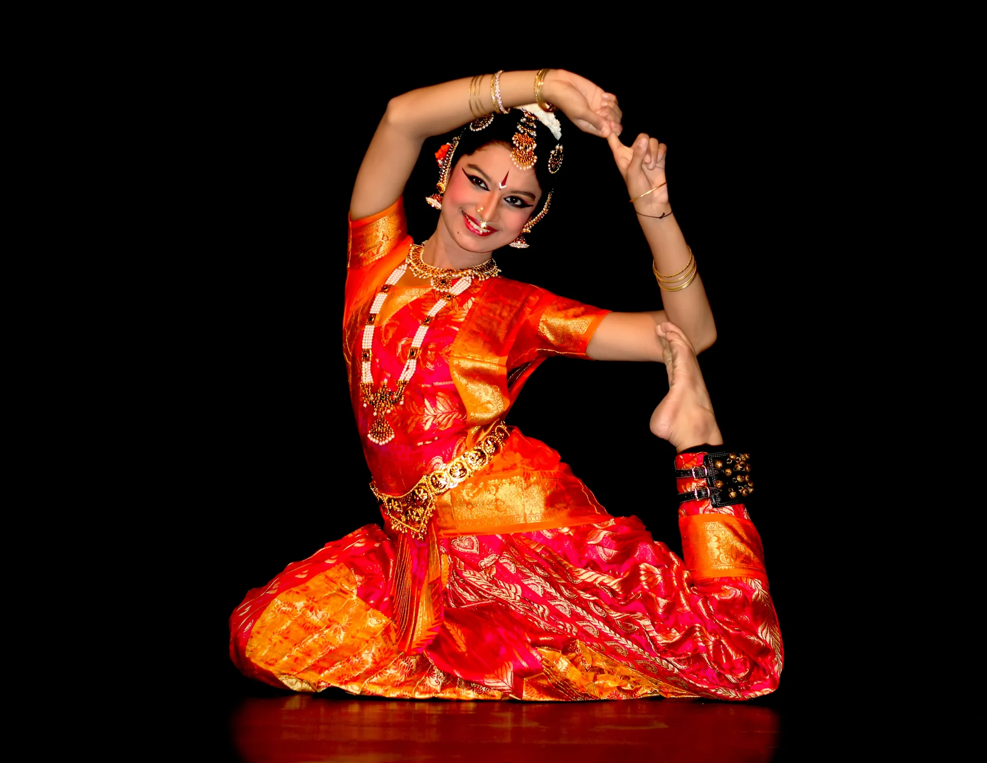 Bharatanatyam dancer demonstrating classical pose with bent legs and expressive mudra