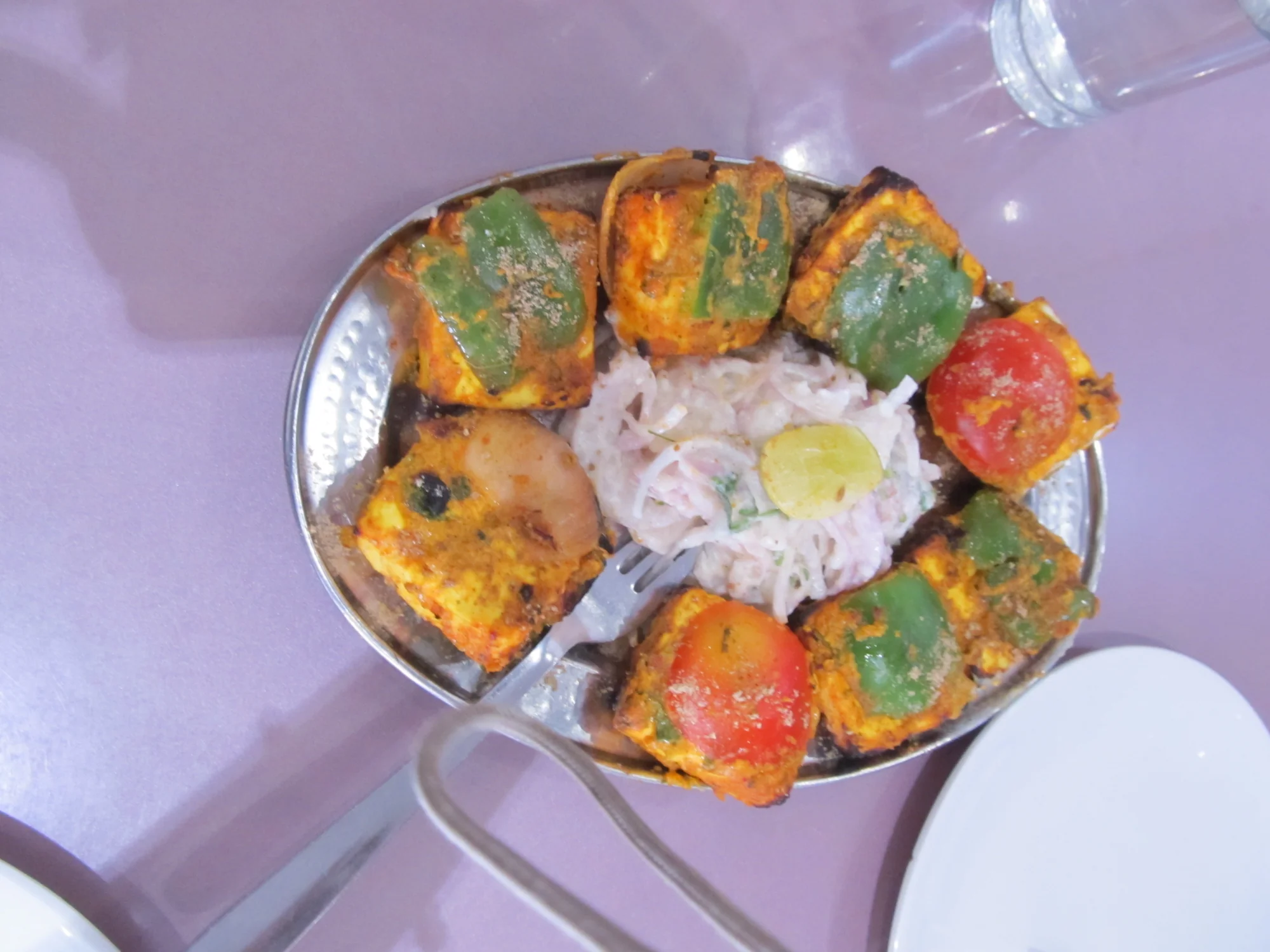 Paneer tikka pieces threaded on skewers ready for grilling