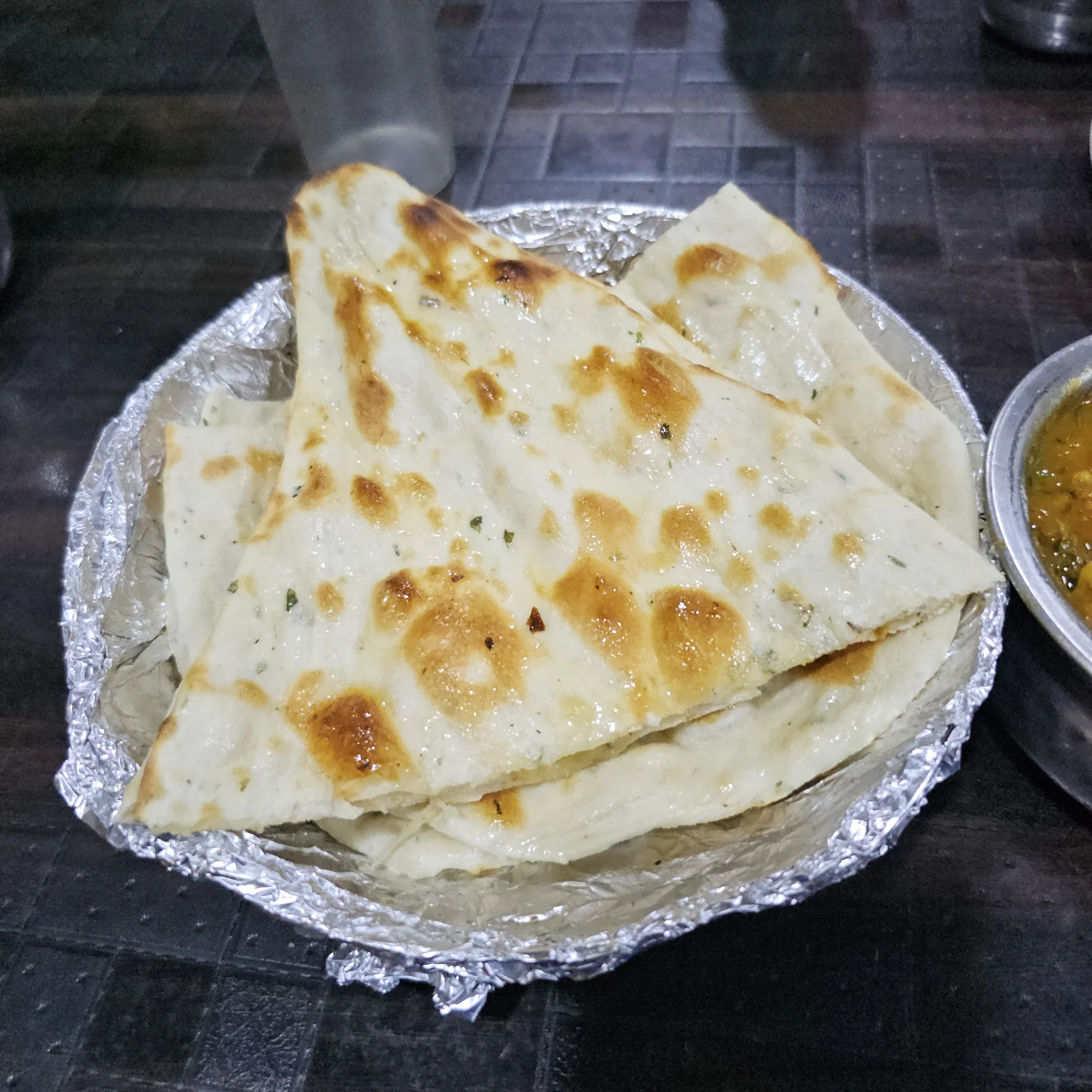 Golden-brown butter naan with characteristic charred spots