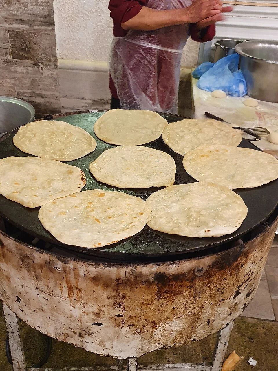 Parathas being prepared on a traditional griddle
