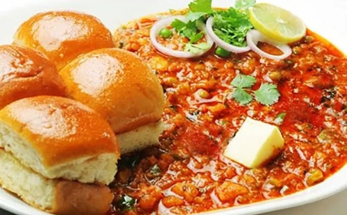 Mumbai-style pav bhaji served on a traditional plate with lemon wedges