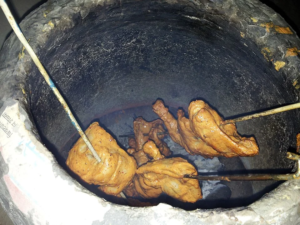 Tandoori chicken displayed with traditional clay tandoor oven