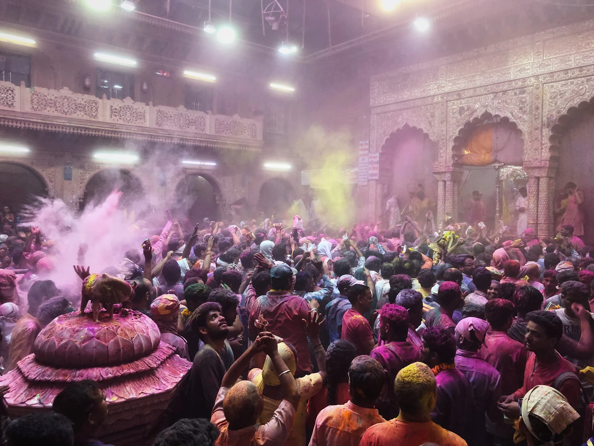 Crowds celebrating Holi festival with colored powder in Mathura